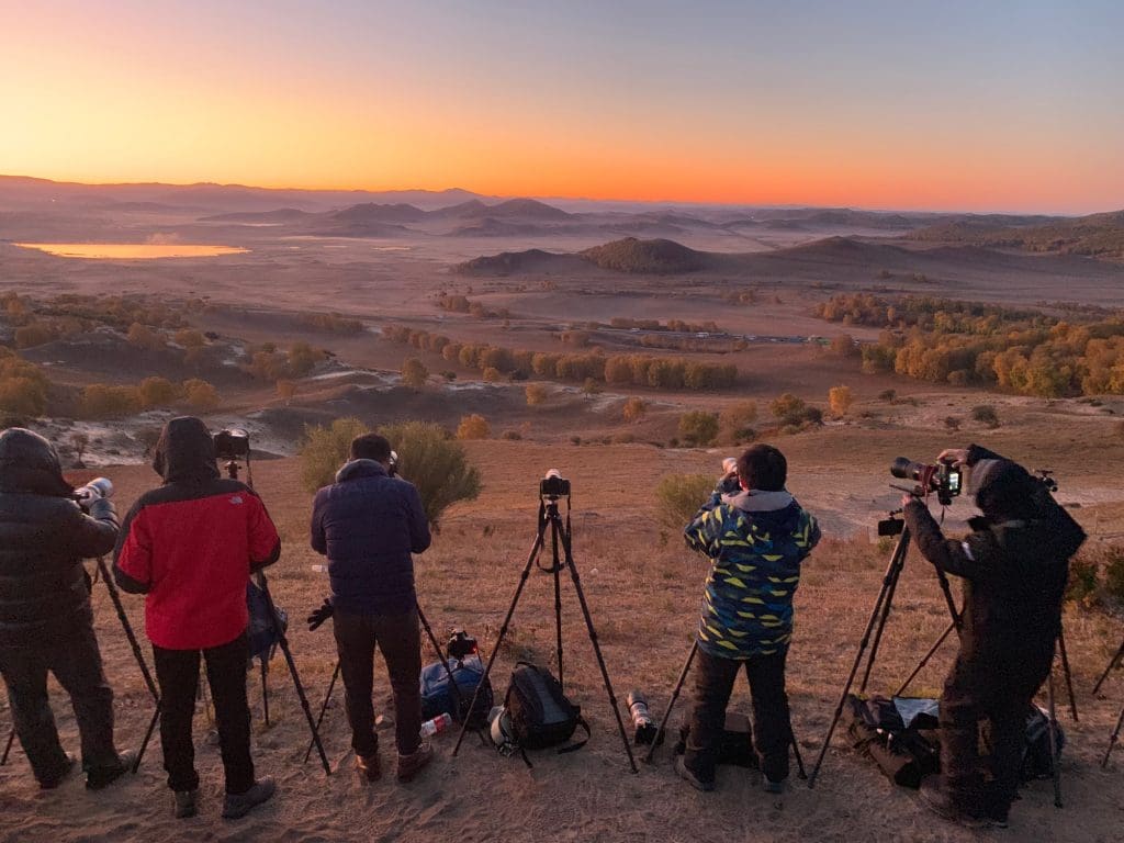 Grupo de personas tomando fotografías al amanecer